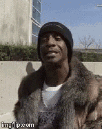 a man wearing a fur coat and a black beanie is smiling .