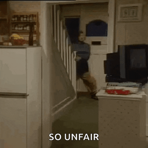 a man is walking down a set of stairs in a kitchen with the words `` so unfair '' written on the bottom .