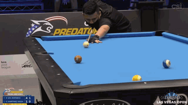 a man is playing pool with a predator logo on the wall behind him