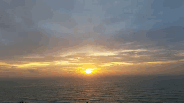 a sunset over a body of water with a cloudy sky