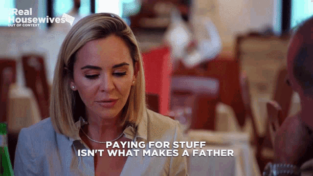 a woman is sitting at a table with a man and the words paying for stuff isn 't what makes a father