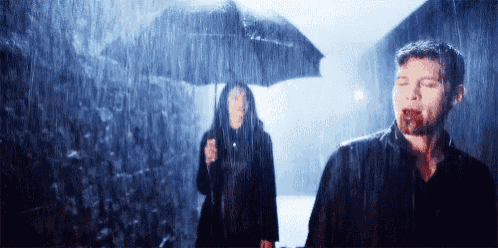 a man and a woman standing in the rain with umbrellas .
