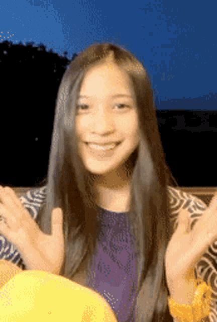 a woman with long black hair is smiling and waving