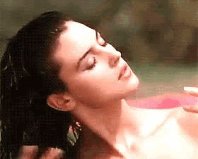 a woman is washing her hair in a bathtub with her eyes closed .
