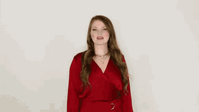 a woman in a red dress is making a funny face and giving a peace sign .
