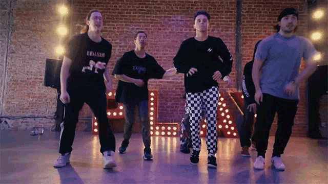 a group of young men are dancing in front of a sign that says l.a.