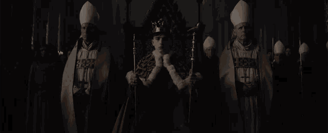 a man in a crown is sitting on a throne in front of a group of priests
