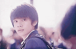a young man with a backpack is standing in front of a crowd of people .