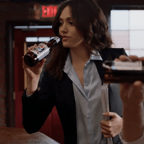 a woman is drinking from a bottle that has a label that says ' stout ' on it
