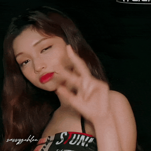 a woman wearing a top that says s on it makes a peace sign