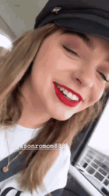 a woman wearing a hat and red lipstick is smiling