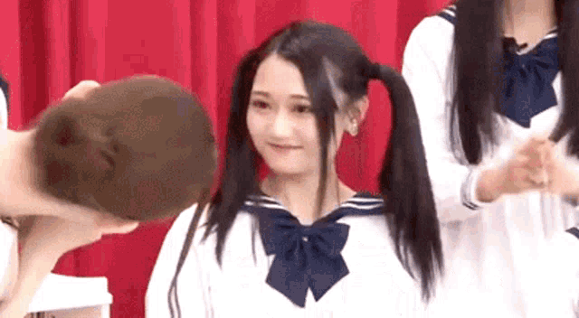 a girl with pigtails is standing next to a man with his head down .