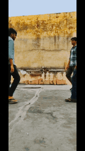 a group of people are walking in front of a wall
