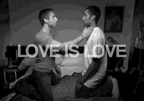 a black and white photo of two men kneeling on a bed with the words love is love above them .