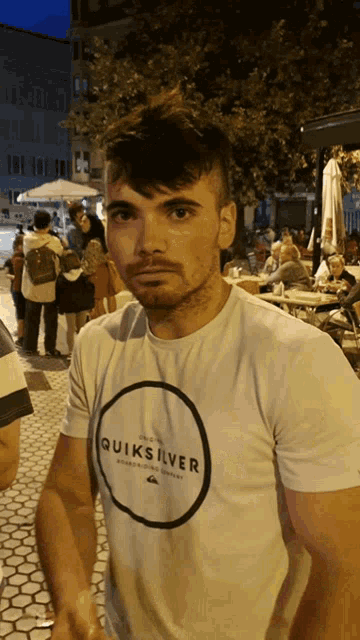 a man wearing a quiksilver t-shirt stands in front of a crowd