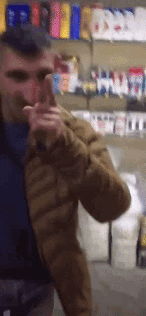 a man in a brown jacket is standing in front of a store
