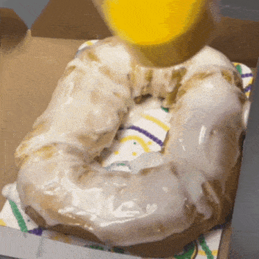 a donut with white frosting is being poured with a yellow liquid