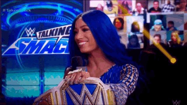 a woman with blue hair is smiling in front of a talking smack sign
