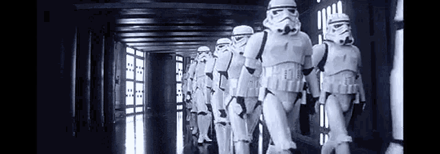 a row of storm trooper soldiers are walking down a hallway .