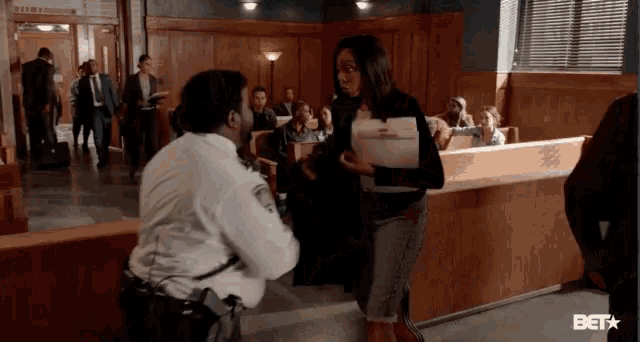 a woman is talking to a police officer in a courtroom with bet written on the screen