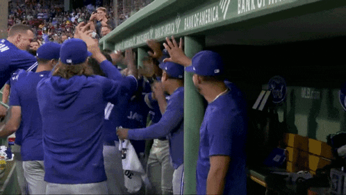 a group of baseball players in a dugout with a bank of america banner above them