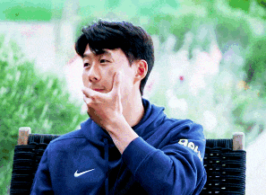 a man in a blue nike hoodie is sitting in a chair with his hand on his mouth .