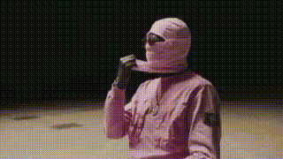a person wearing a pink ski mask and gloves is holding a piece of paper in their hand .