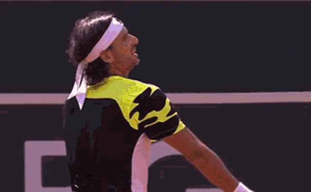 a man wearing a headband is playing tennis with the letter r behind him