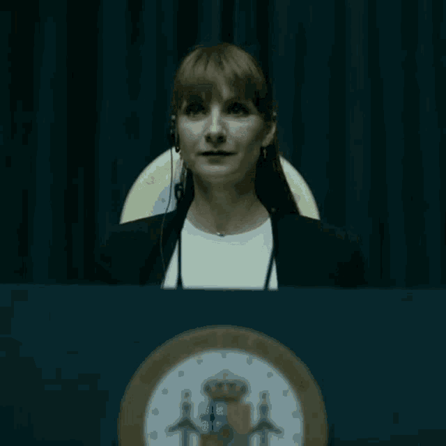 a woman is standing at a podium wearing a headset and a microphone .