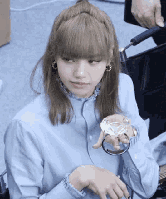 a woman in a blue shirt is holding a diamond in her hands .