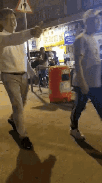 a group of people walking down a street at night with a sign that says ' a ' on it