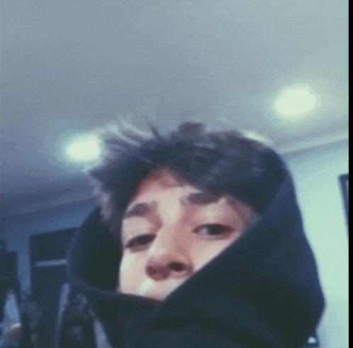 a young man wearing a black hoodie looks at the camera