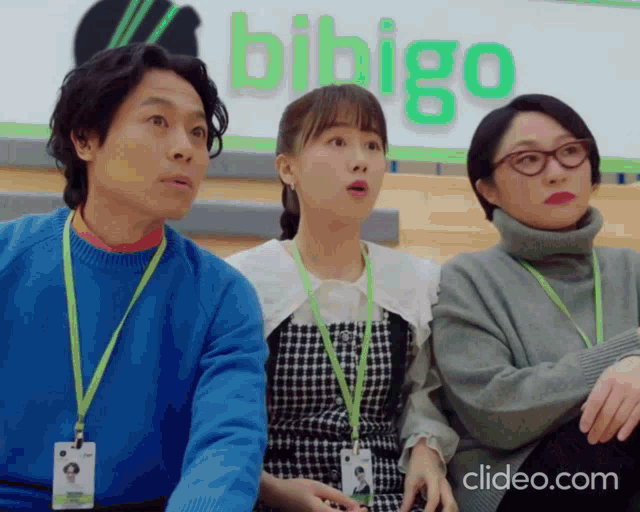 a group of people are sitting in front of a bibigo sign