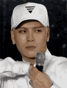 a man wearing a white hat is holding a microphone in his hand .
