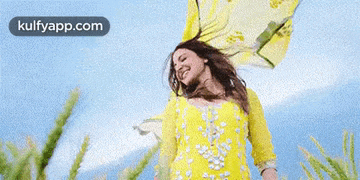 a woman in a yellow dress is standing in a field