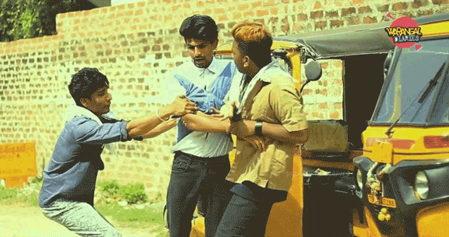 a group of men are standing in front of a yellow rickshaw with a sticker on it that says ' warangal '