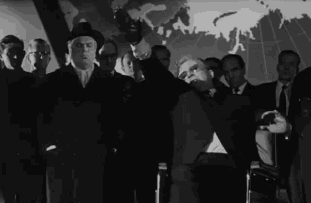 a group of men are standing in front of a large map of the world .