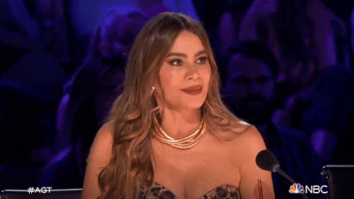 a woman is smiling while sitting in front of a microphone on a stage .