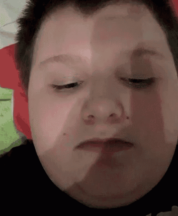 a close up of a boy 's face with his eyes closed