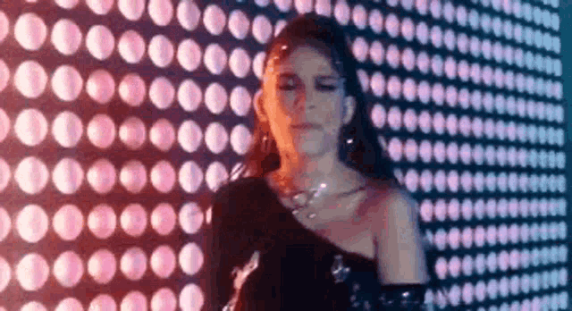 a woman is standing in front of a wall with a lot of lights on it .