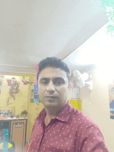 a man in a red shirt is taking a selfie in front of a wall with a calendar on it