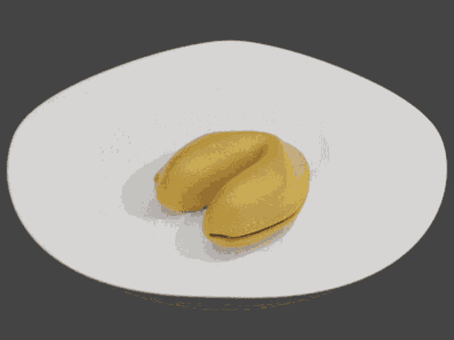 a white plate with a yellow fortune cookie on it