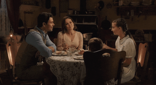 a family sits around a table with plates of food on it