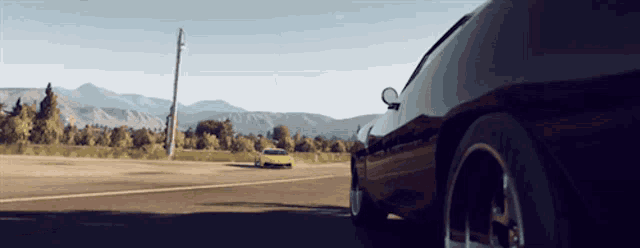 a yellow car is driving down a road next to a red car