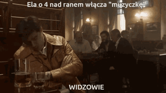 a man in a leather jacket sits at a table with a glass of beer in front of him in a bar