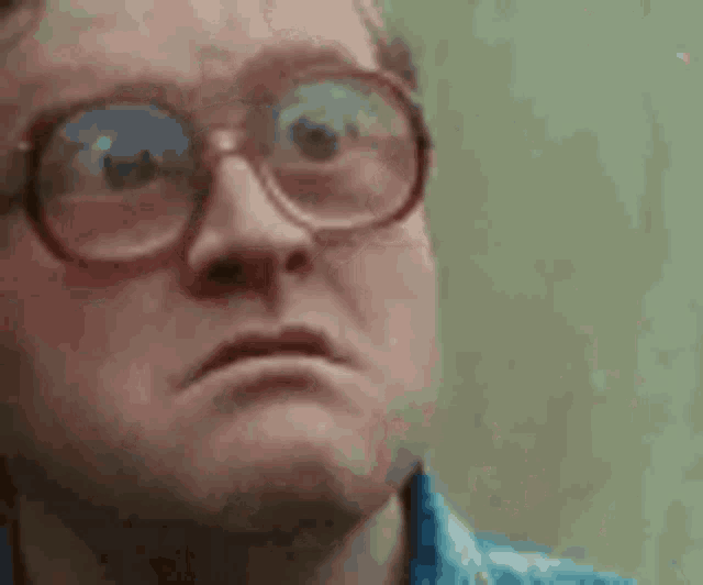 a man wearing glasses and a blue shirt is making a face .