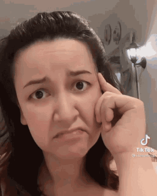 a woman is making a funny face while holding her hand to her ear .