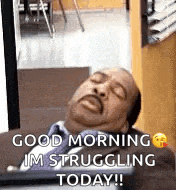 a man in a suit and tie is sleeping on a desk with his eyes closed .