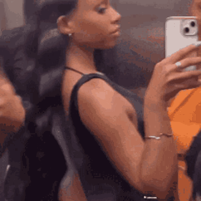 a woman is taking a selfie with her phone in an elevator .