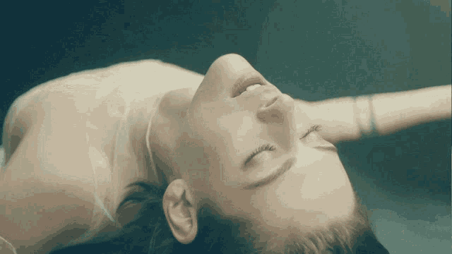 a woman laying down with her eyes closed and her mouth open
